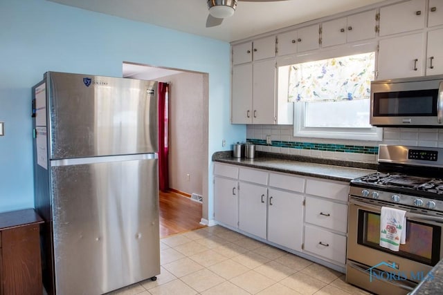 kitchen featuring tasteful backsplash, visible vents, a ceiling fan, dark countertops, and stainless steel appliances