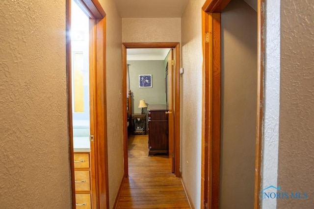 hallway with a textured wall and wood finished floors