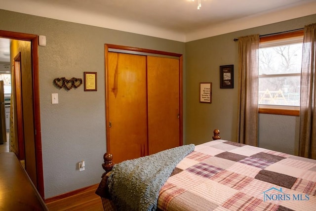 bedroom featuring a textured wall, a closet, and wood finished floors