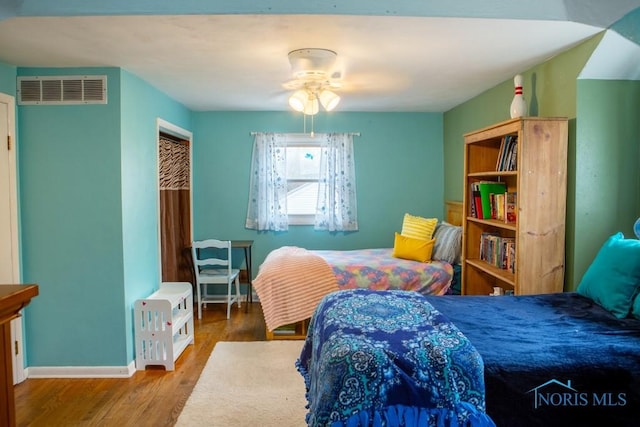 bedroom with baseboards, visible vents, and wood finished floors