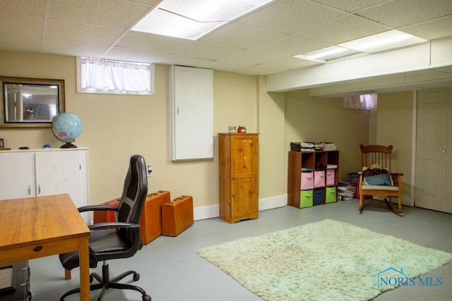 home office with concrete flooring, a drop ceiling, and baseboards