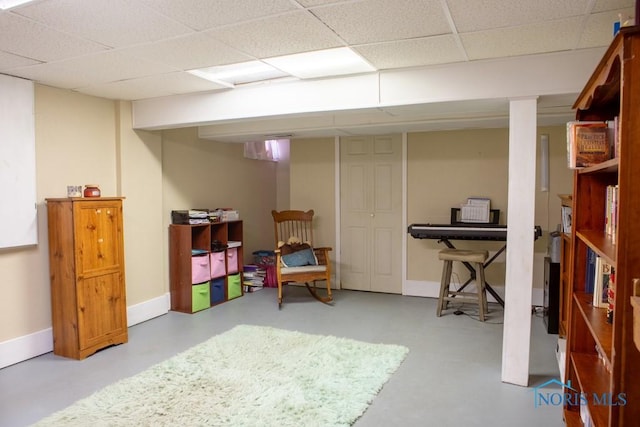 finished basement with a paneled ceiling and baseboards