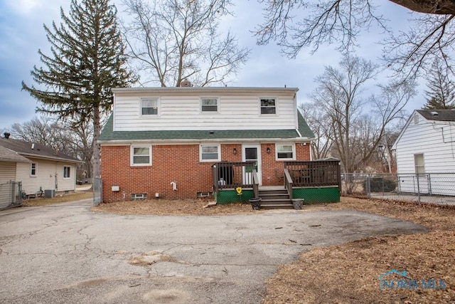 view of front of house with brick siding, driveway, and fence