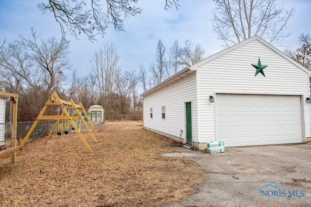 exterior space featuring a garage, a playground, and an outbuilding