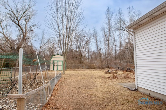 view of yard featuring a garden, fence, a storage unit, and an outbuilding