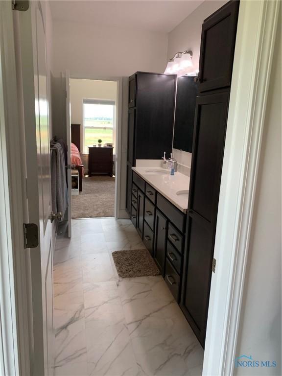 ensuite bathroom with marble finish floor, double vanity, a sink, and ensuite bathroom