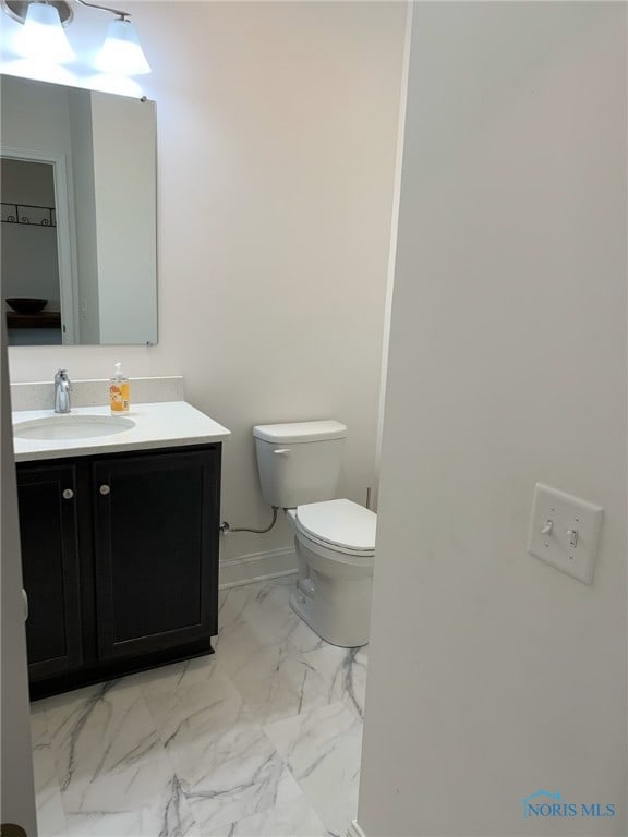 bathroom with toilet, marble finish floor, baseboards, and vanity