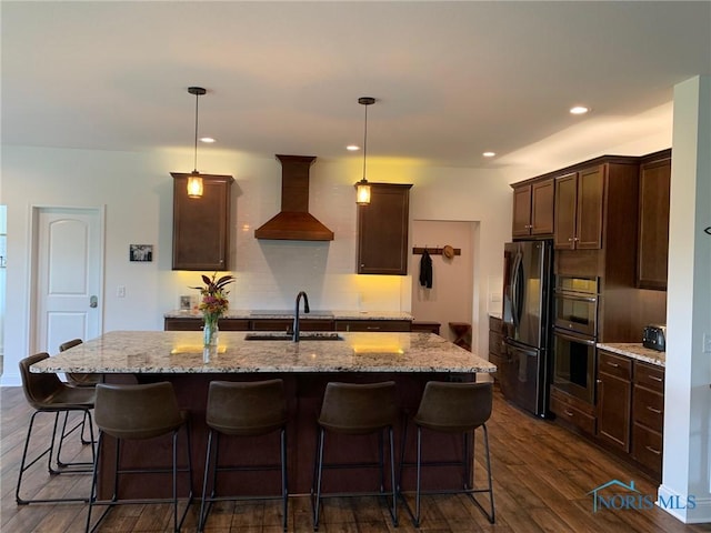 kitchen featuring dark wood finished floors, custom range hood, freestanding refrigerator, dark brown cabinets, and a sink