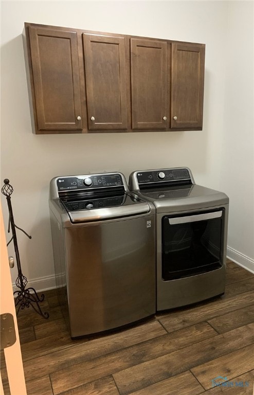 laundry room featuring dark wood-type flooring, independent washer and dryer, cabinet space, and baseboards