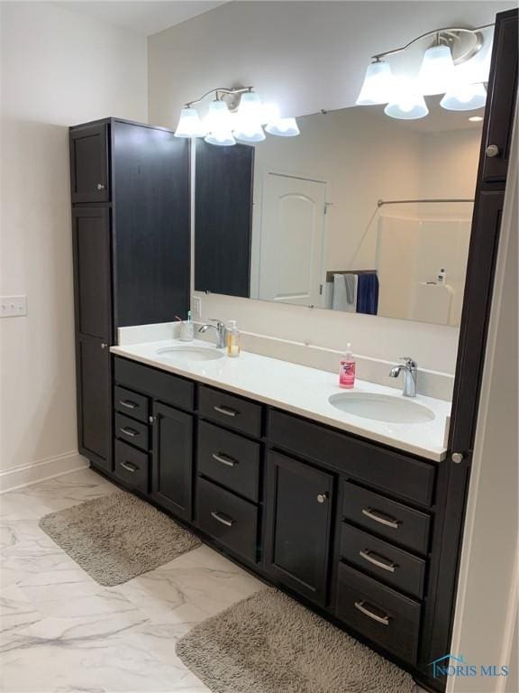 bathroom with marble finish floor, a sink, and double vanity