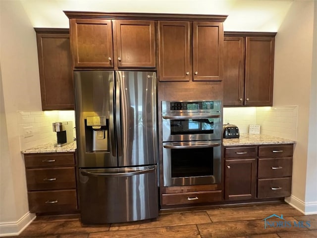 kitchen featuring baseboards, stainless steel appliances, tasteful backsplash, and light stone countertops