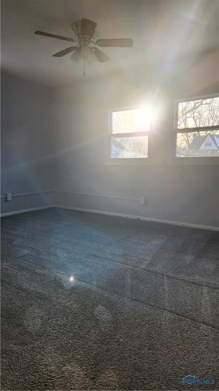 unfurnished room featuring a ceiling fan and baseboards