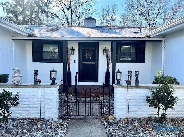 entrance to property with a shingled roof, a chimney, fence, and a porch