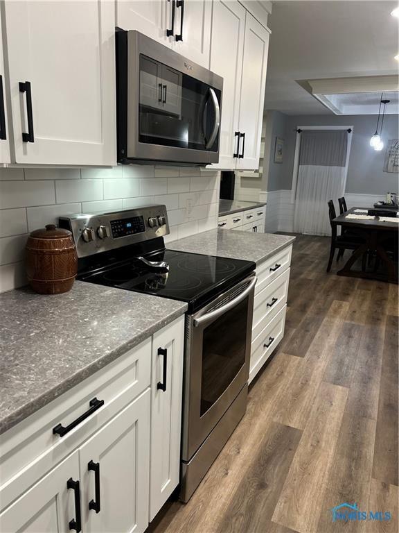 kitchen with dark wood finished floors, white cabinetry, and stainless steel appliances