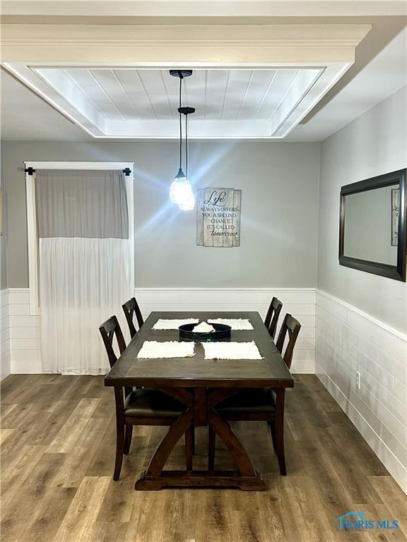 dining space featuring beam ceiling, a wainscoted wall, and wood finished floors