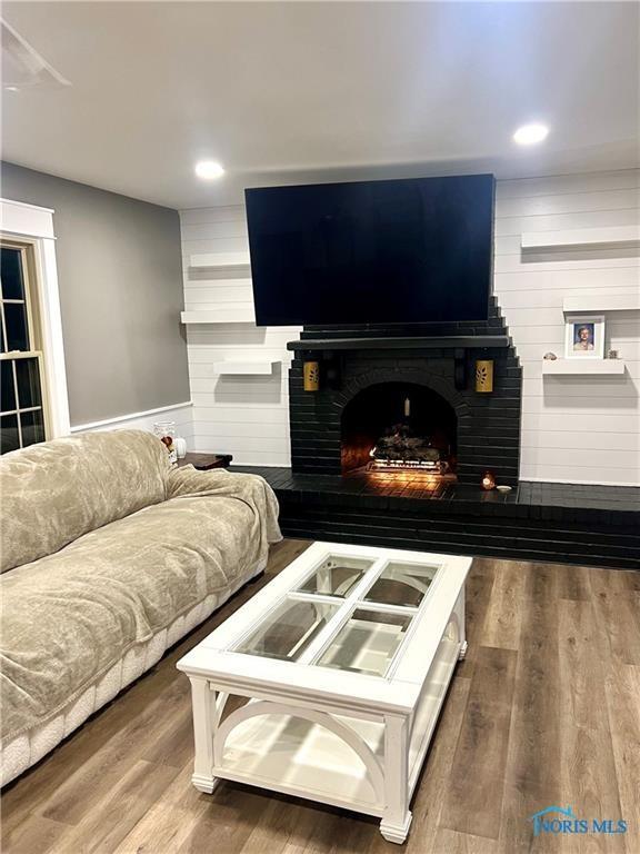 living room featuring recessed lighting, a fireplace, and wood finished floors