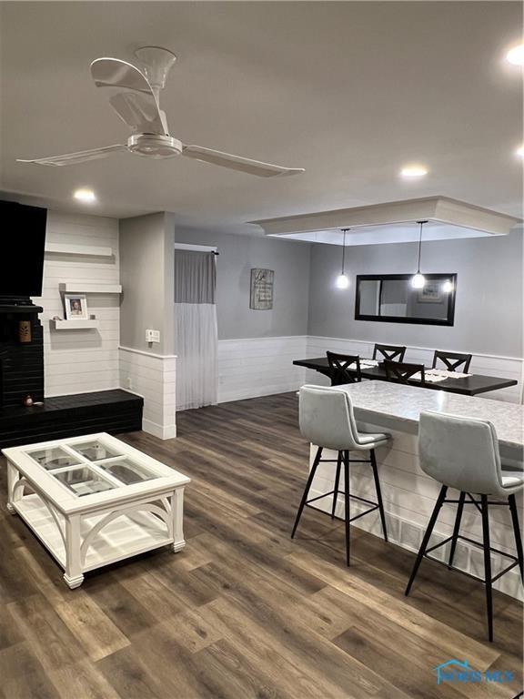 kitchen featuring dark wood-type flooring, wainscoting, and a breakfast bar area