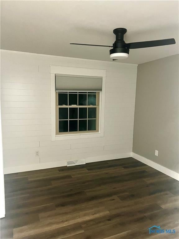 empty room featuring ceiling fan, wood finished floors, and baseboards