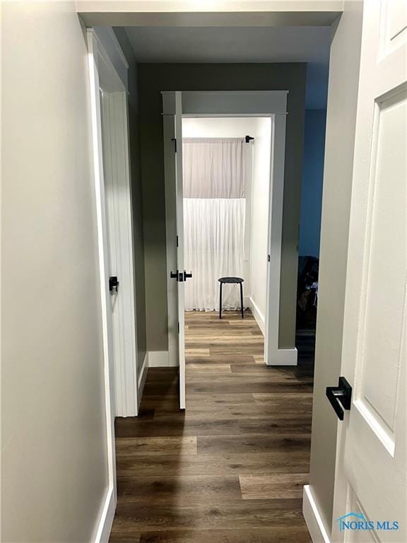 hallway with dark wood finished floors and baseboards