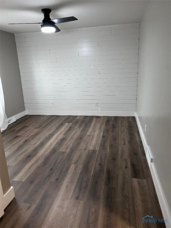 spare room with visible vents, a ceiling fan, baseboards, and dark wood-style flooring