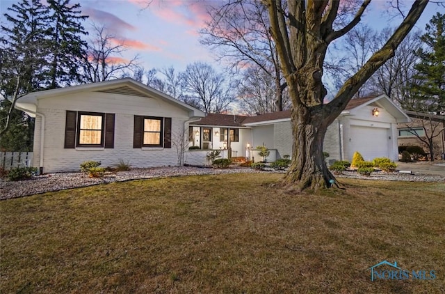 single story home featuring brick siding, a garage, and a yard