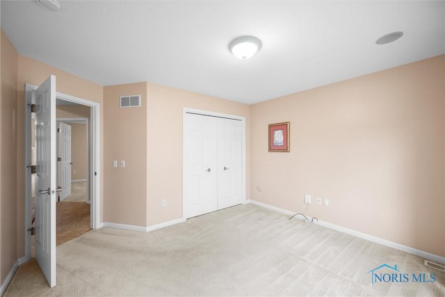 unfurnished bedroom with baseboards, a closet, visible vents, and light colored carpet