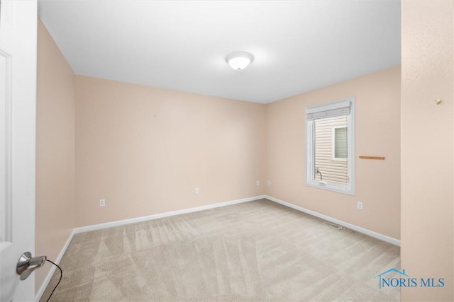 carpeted spare room featuring visible vents and baseboards