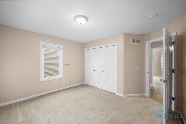 unfurnished bedroom featuring a closet, visible vents, light carpet, and baseboards