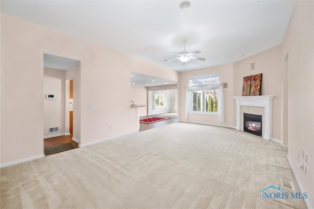 unfurnished living room with carpet, a tile fireplace, visible vents, and baseboards