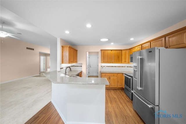 kitchen featuring stainless steel appliances, tasteful backsplash, visible vents, light wood-style flooring, and a peninsula