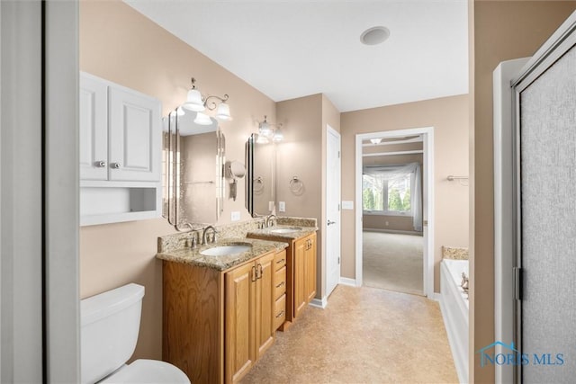 bathroom with double vanity, a sink, toilet, and a tub