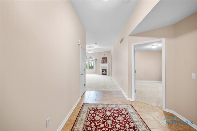 corridor with carpet floors, tile patterned flooring, visible vents, and baseboards