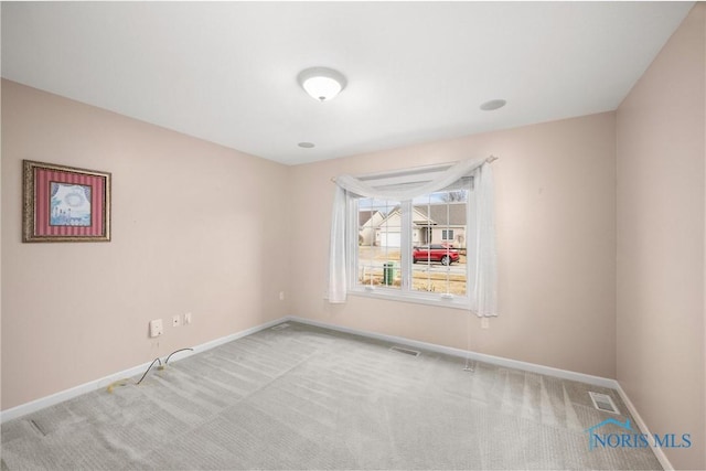 carpeted spare room with visible vents and baseboards