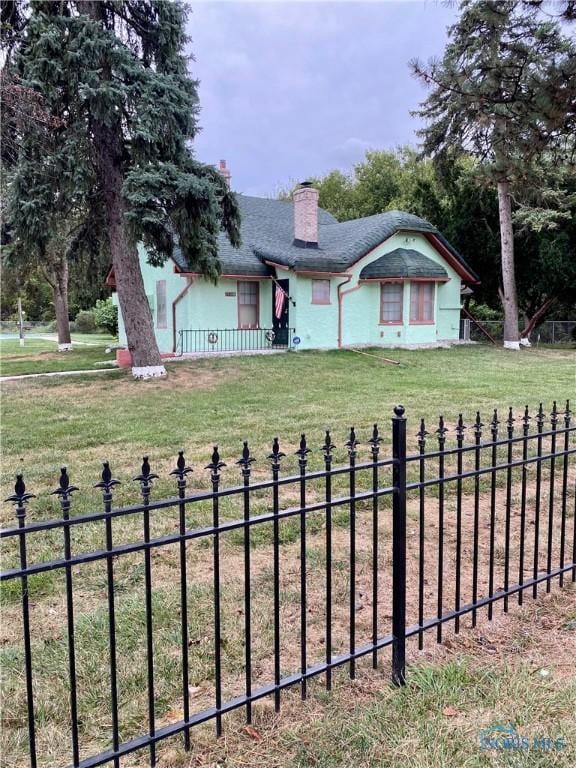 view of front of property with a front lawn, a chimney, and fence