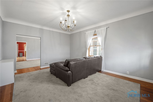 living room featuring baseboards, visible vents, a notable chandelier, and wood finished floors