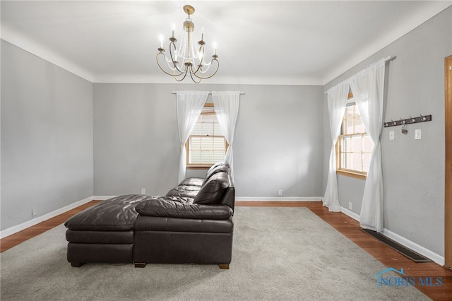 sitting room with a notable chandelier, baseboards, and wood finished floors