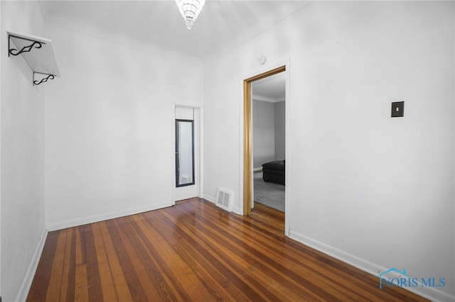 unfurnished room featuring dark wood-style floors, baseboards, and visible vents