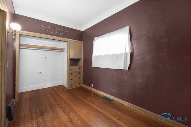 unfurnished bedroom featuring baseboards, visible vents, and wood finished floors