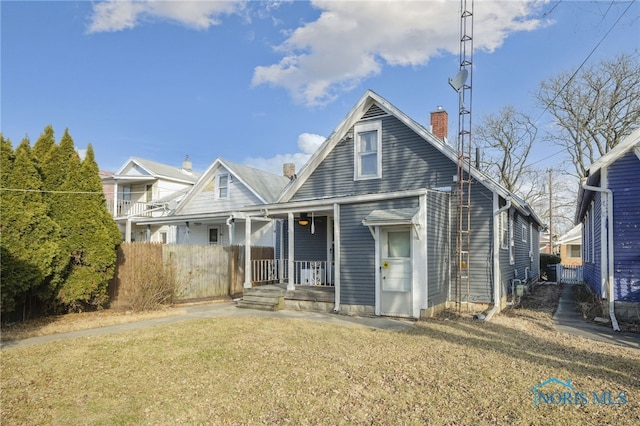 view of front of property with covered porch, a chimney, and a front lawn