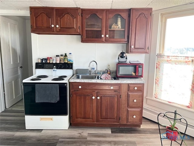 kitchen featuring electric stove, light countertops, light wood-style flooring, baseboard heating, and a sink