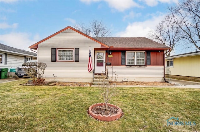 bungalow-style house with entry steps, roof with shingles, a front lawn, and board and batten siding