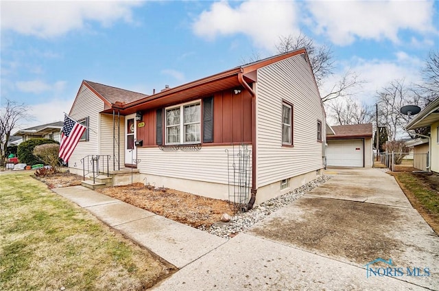 bungalow-style home with a detached garage, fence, driveway, a front lawn, and board and batten siding