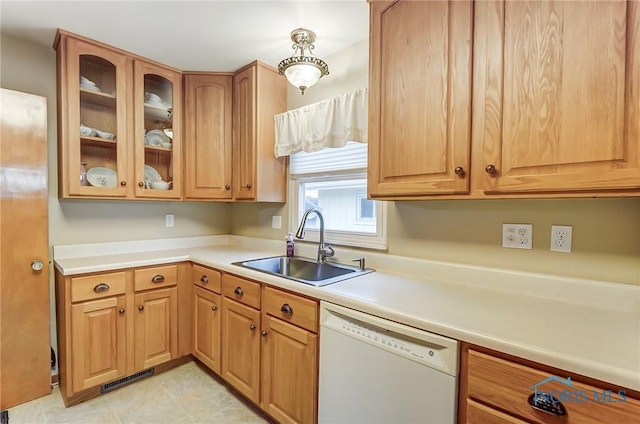 kitchen featuring glass insert cabinets, light countertops, dishwasher, and a sink