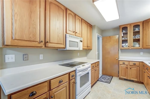 kitchen with light countertops, white appliances, and glass insert cabinets