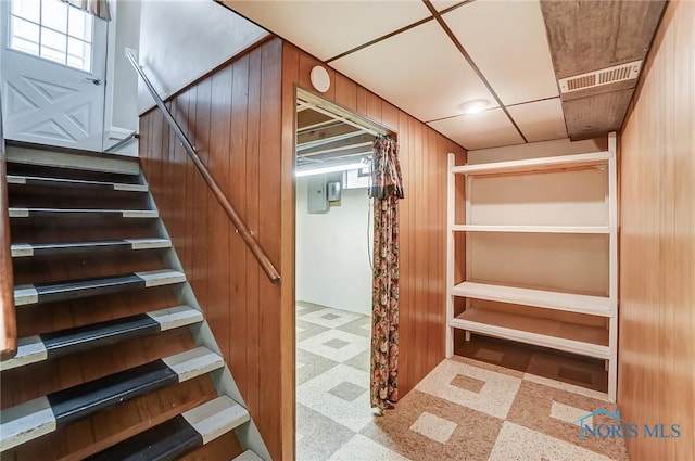 staircase featuring wood walls, visible vents, and tile patterned floors