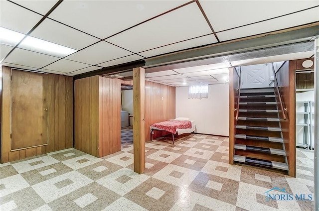 basement with a paneled ceiling, wood walls, stairs, tile patterned floors, and washer / dryer