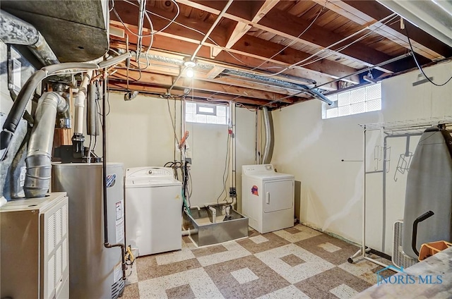 below grade area with water heater, washing machine and clothes dryer, and tile patterned floors