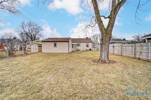 back of house featuring a fenced backyard and a lawn