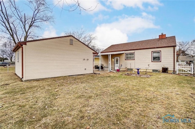 rear view of house with a yard, a chimney, a patio area, central AC, and fence