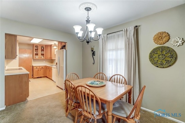 dining space featuring baseboards, light colored carpet, and an inviting chandelier